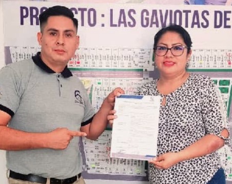 Clienta recibiendo su documentación frente al plano del proyecto